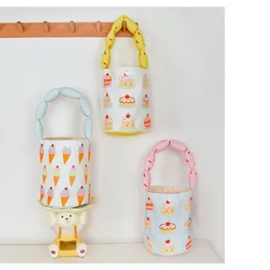 Detailed shot of cute canvas bucket bag with sweet cake and ice cream prints, bubble handle.