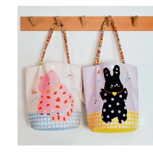 Cute canvas tote bag with cartoon cat and rabbit pattern, stylish shoulder handbag for daily use.