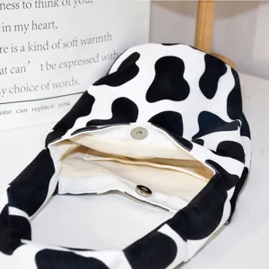 Black and white cow print canvas tote bag, stylish handbag with magnetic snap closure.