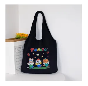 Detail view of black canvas tote bag featuring cute cartoon animals and tomato graphic print.