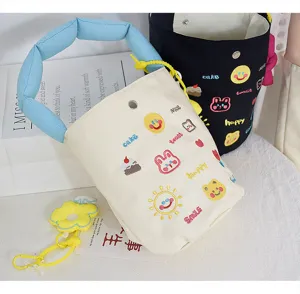Canvas bucket bag with letter embroidery, cute cartoon patches, and soft blue handle.