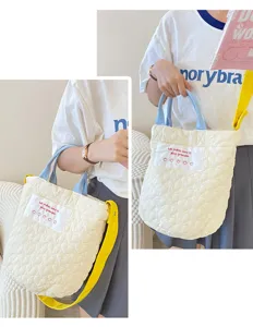 Quilted crossbody bag detail showcasing heart pattern, blue handles, and yellow strap clearly.