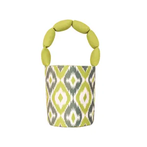 Canvas bucket handbag with unique round padded handle and green geometric ikat pattern.