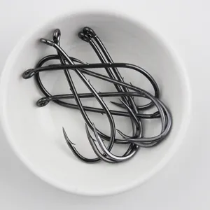Close-up detail shot of black fishing hooks with barbs and ringed shanks inside a white bowl.