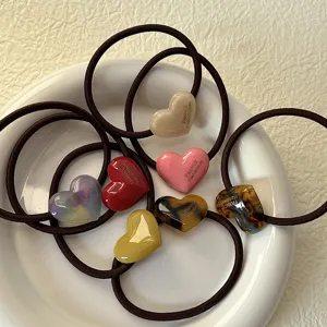 Vista dettagliata di simpatici elastici per capelli a cuore in acetato colorato.