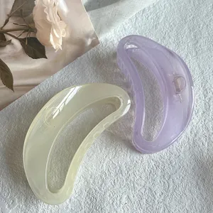 Detail shot of translucent jelly crescent hair claw clips in pastel yellow and soft purple tones.