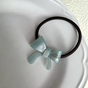 Detail view of the elegant light blue acetate bow hair tie, perfect for stylish ponytail styling.