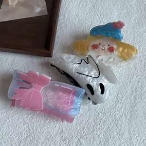 Detailed view of cute acrylic hair claws featuring cartoon character, ghost and bow designs.