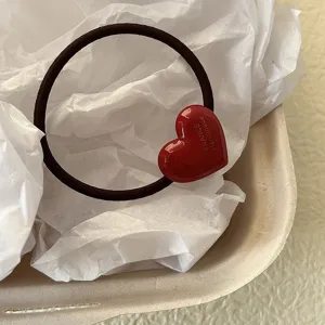Primo piano dettagliato del simpatico elastico per capelli a cuore rosso con finitura.