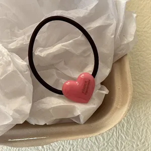 Dettaglio in primo piano del dolce elastico per capelli a cuore rosa con finitura lucida.