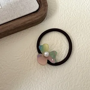 Detailed close-up shot of the colorful acetate flower hair tie featuring a central pearl accent.