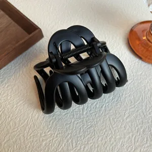 Matte black hair claw clip detail shot, showing textured surface and sturdy metal spring.