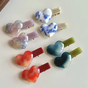 Detailed view of fashionable acetate heart hair clips featuring beautiful marbled color designs.
