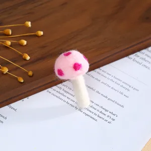 Close-up detail of a cute pink wool felt mushroom with white dots, handmade DIY craft accessory.