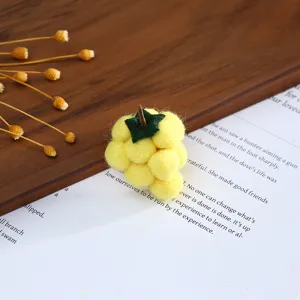 Close-up detail of yellow wool felt grape accessory for DIY hats and handmade hair clips.