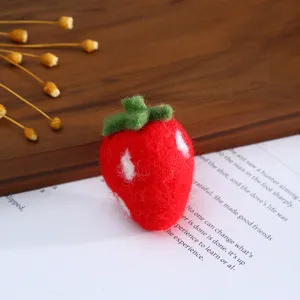 Close-up detail of handmade wool felt strawberry, cute DIY craft accessory for hair clip.