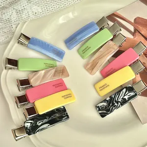 Detailed shot of colorful acetate hair clips, metallic duckbill clip design, aesthetic accessories.