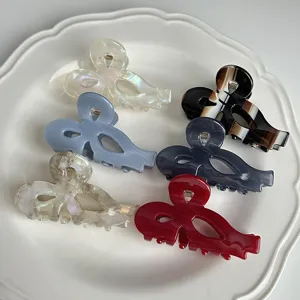 Close-up detail of cute hollow bow hair claws in various colors and patterns, elegant acetate shark clips.