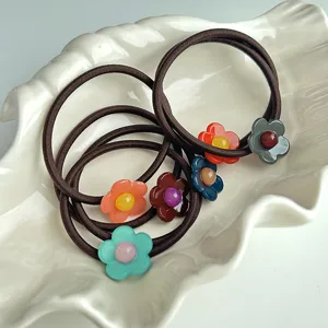Charmants élastiques marrons avec pendentifs fleurs en résine, détail doux pour coiffure.