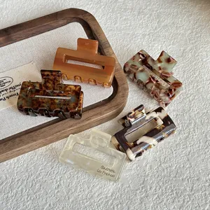 Detailed shot of small acetate hair claw clips in various stylish tortoise shell patterns and colors.