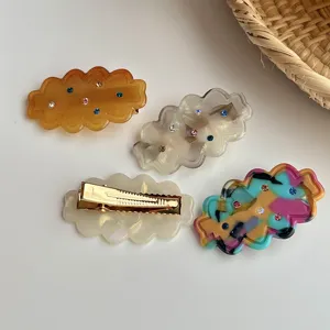 Detail shot of wavy rhinestone hair clips with colorful crystals and gold-tone alligator clips.