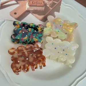 Detailed view of colorful acetate hair claw clips with rhinestone details and wavy cookie design.