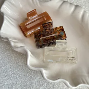 Detailed view of small cellulose acetate hair claw clips set in shell tray, chic hair accessory.