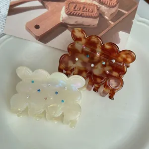 Acetate hair claw featuring a cute cookie shape, colorful rhinestones, and elegant wavy edges.