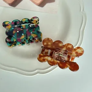 Detail shot of cute acetate hair claw clips with wavy design and sparkling rhinestones.