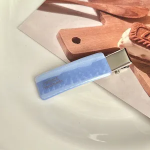 Chic light blue acetate hair clip detail close-up, elegant side hairpin accessory.