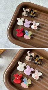 Close-up detail of cute acetate hair claw clips with rhinestone bow design, assorted colors.