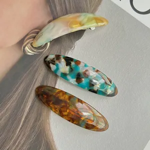Detailed view of elegant acetate hair clips featuring chic tortoiseshell patterns and metal clips.
