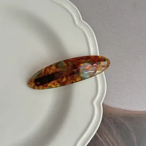 Tortoise shell acetate hair clip detail shot, vintage oval design hairpin for elegant hairstyles.
