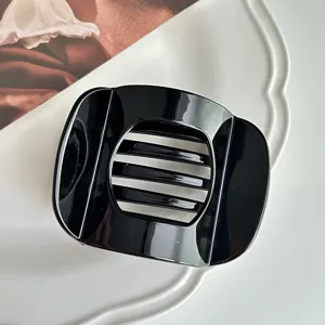 Detailed close-up of a glossy black curved hair claw clip, sleek minimalist design, texture.