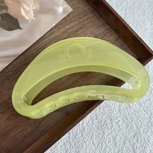 Closeup of translucent yellow-green jelly hair claw clip, simple design on wooden tray.