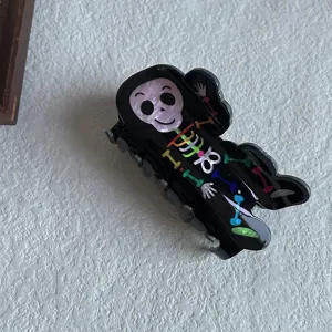 Black acrylic hair claw clip featuring a cute cartoon skeleton design, trendy styling detail.