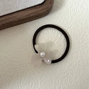 Close-up detail of a French retro acetate flower hair tie with pearl center and elastic band.