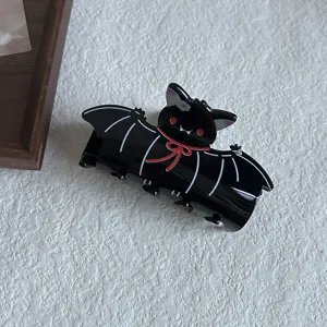 Close up view of a cute black bat acrylic hair claw clip featuring red ribbon details and sharp claws.