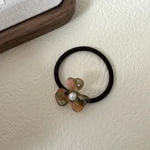 Detail shot of a French vintage acetate flower hair tie with pearl accent for elegant hairstyles.