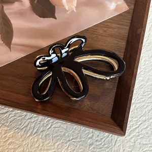 Primo piano del dettaglio del fermaglio per capelli a farfalla nero e oro, elegante.