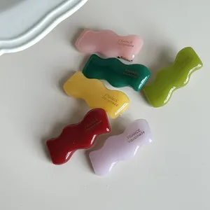 Primo piano di fermagli per capelli ondulati in acetato colorato, stile caramella dolce.