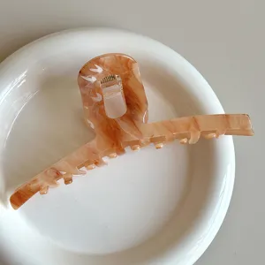 Large hair claw clip with stylish amber tortoiseshell pattern, perfect for thick hair styling.