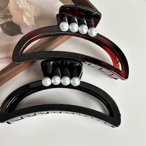 Elegant pearl accented crescent hair claw clips in classic black and tortoiseshell, detail view.
