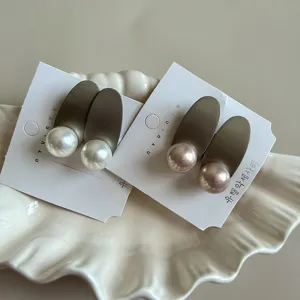 Pearl hair clip detail showcasing elegant oval metal base and lustrous pearls on display card.