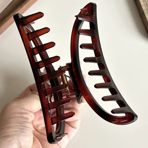 Close-up view of a large brown resin hair claw clip showing the sturdy metal spring mechanism.