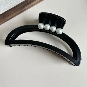 Matte black crescent hair claw clip with pearls, French minimalist shark clip for styling.