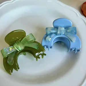 Vista dettagliata di piccoli mollettoni per capelli con fiocco in acetato verde e blu.