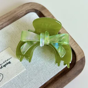 Primo piano di molletta per capelli in acetato verde con fiocco iridescente per stile elegante.