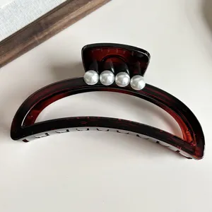Elegant crescent hair claw clip featuring four pearls for styling, detailed view of accessory.