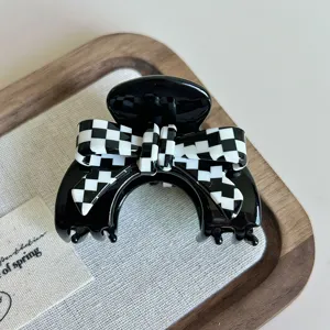 Primo piano di un morsetto per capelli in acetato con fiocco a quadri nero e bianco, elegante.